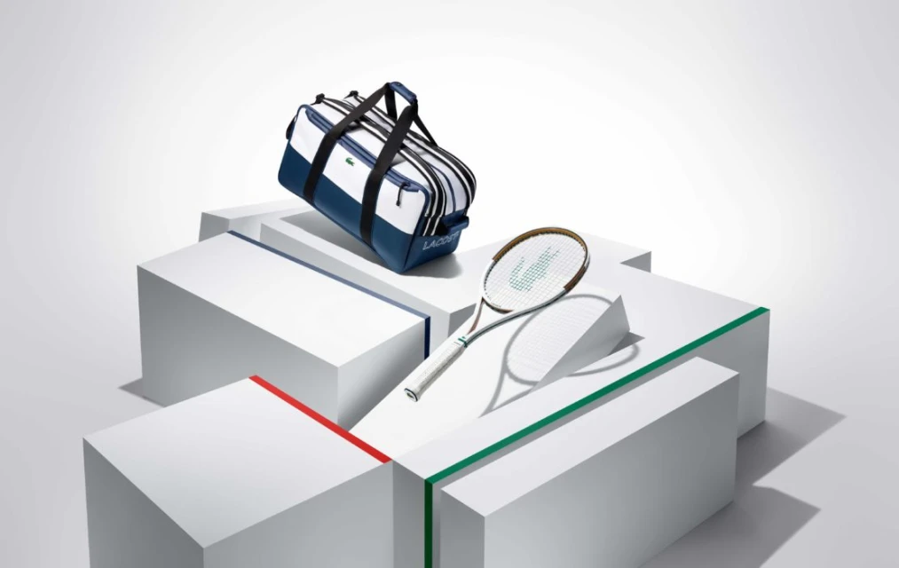 Lacoste tennis bag and racket on white geometric platforms, product shot for advertising, clean modern style, blue, white, green and red.