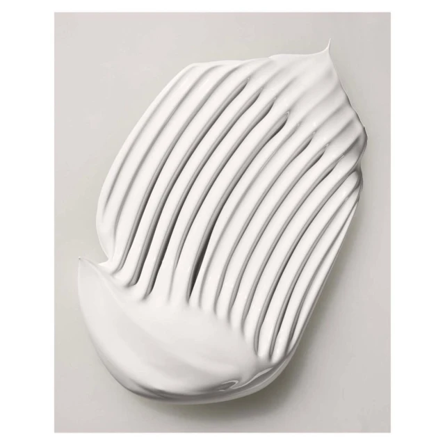 Close-up shot of a swirl of white cream product with distinct ridges, set against a light grey backdrop, highlighting the texture.