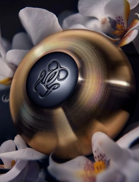 Close-up studio shot of a gold-toned cosmetic container surrounded by white orchid flowers, emphasizing luxury and beauty.