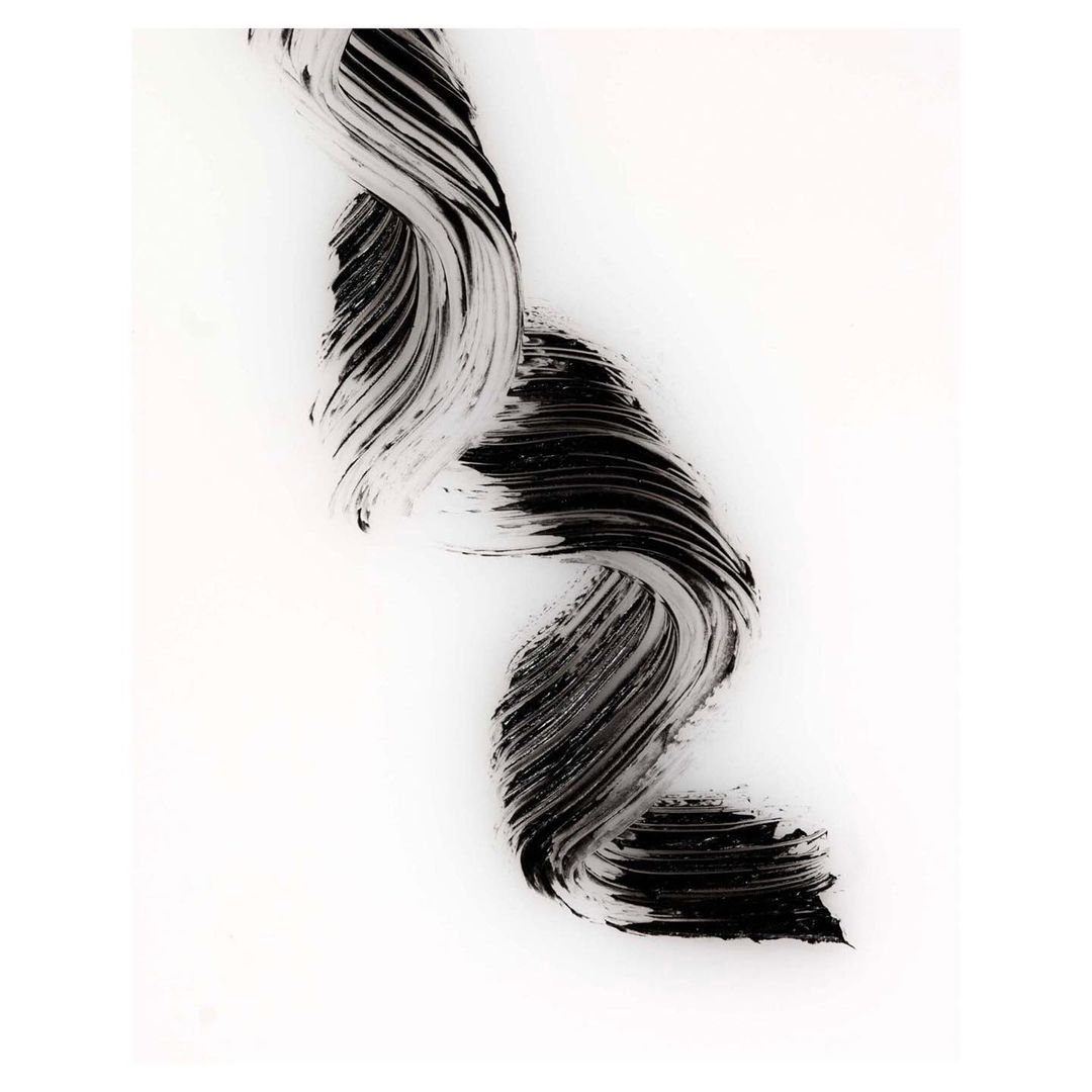 Close-up of textured black mascara smear on white background. Abstract beauty shot for cosmetics, artistic use of makeup, and beauty advertising.