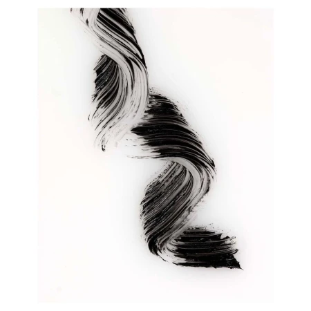 Close-up of textured black mascara smear on white background. Abstract beauty shot for cosmetics, artistic use of makeup, and beauty advertising.