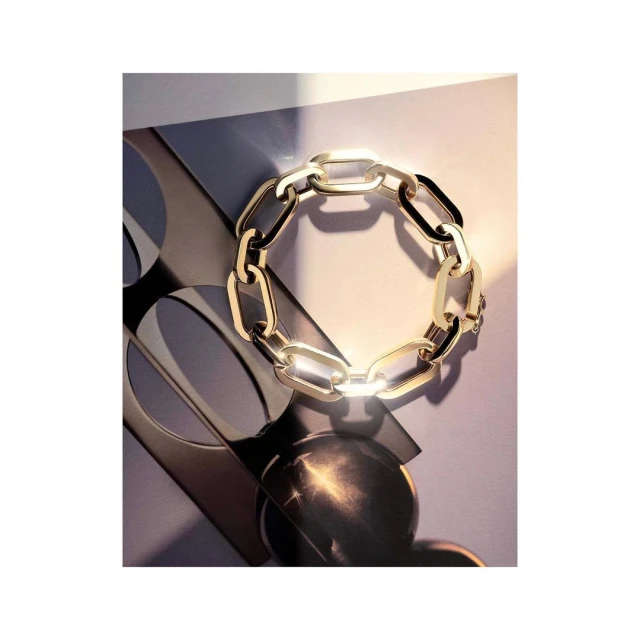 Elegant gold chain bracelet on a stylish grey and cream background with geometric shapes and soft light, conveying luxury and fashion.