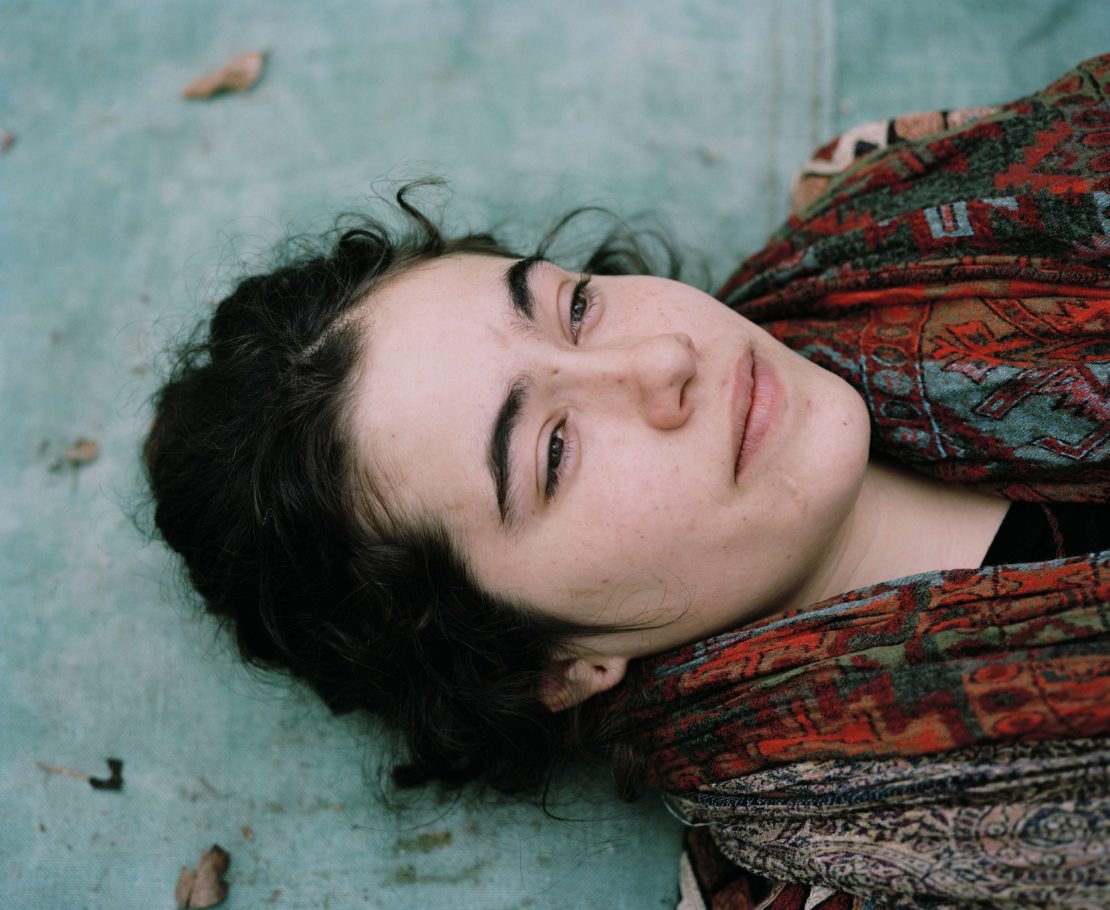 Close-up portrait of a young woman lying down wearing a patterned red and green scarf photographed by Spencer Murphy.