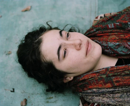 Close-up portrait of a young woman lying down wearing a patterned red and green scarf photographed by Spencer Murphy.
