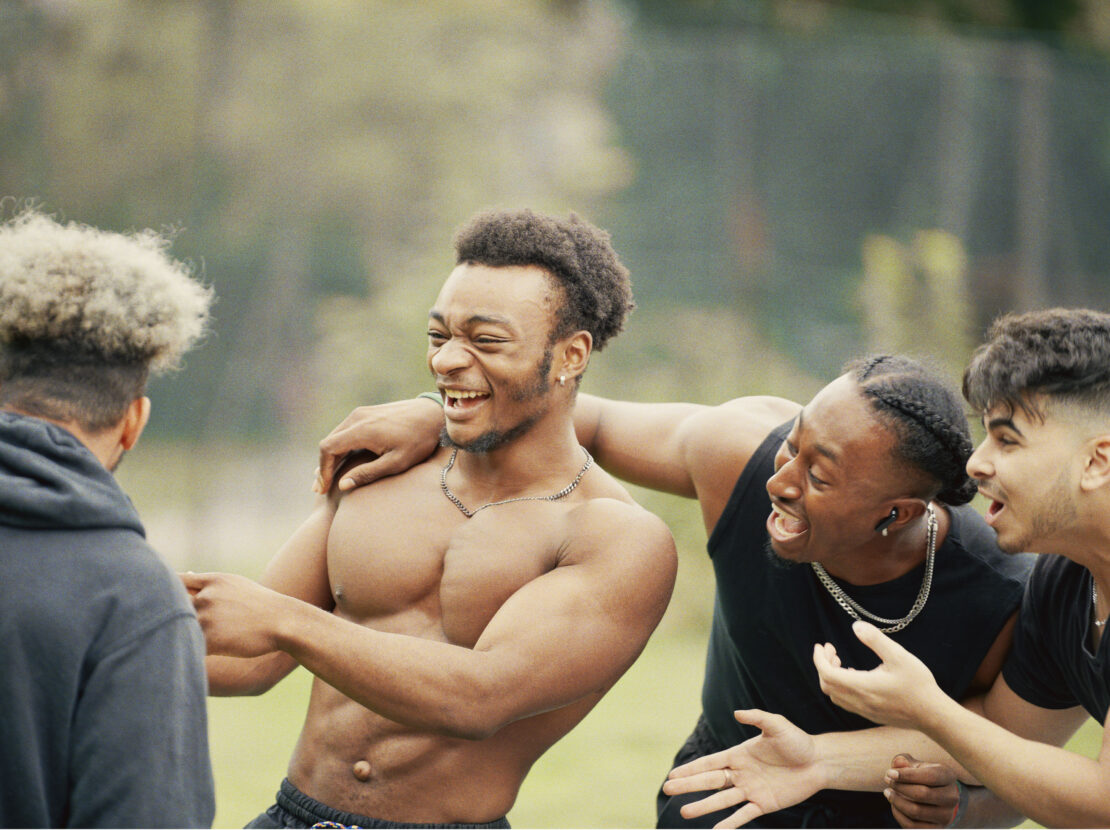 Four young men laughing and interacting outdoors in a park captured in a candid moment by photographer Spencer Murphy
