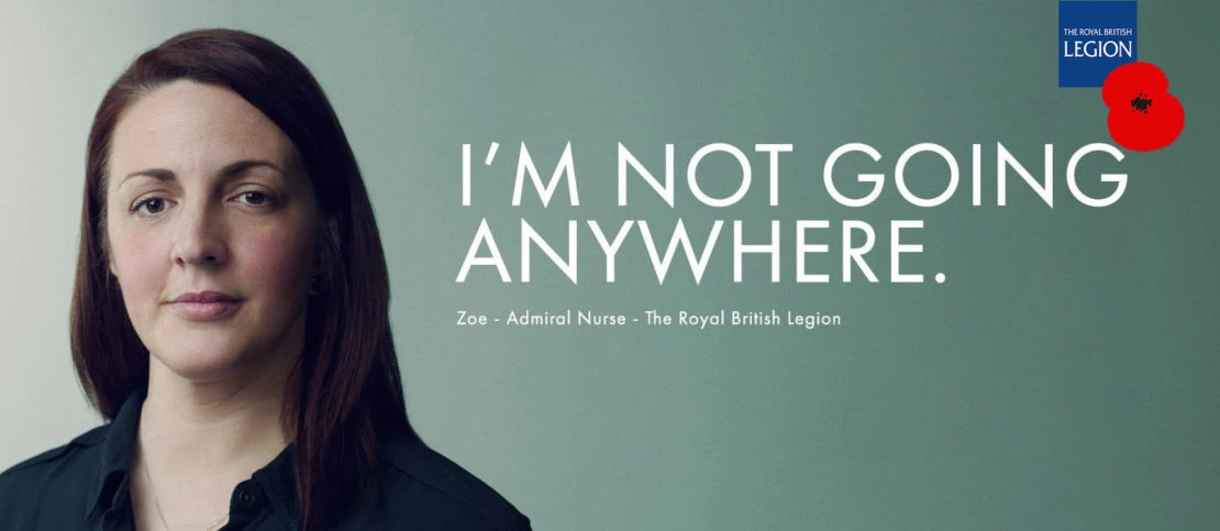 Close-up shot of an adult female with The Royal British Legion poppy logo. Woman is an admiral nurse, photographed indoors.