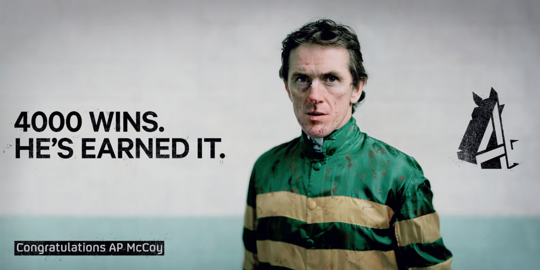 AP McCoy in green and gold racing silks with mud smudges on his face against a pale wall, photographed by Spencer Murphy.