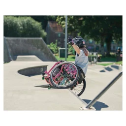 Skater in a helmet using a pink wheelchair on a concrete skatepark ramp, photographed by Spencer Murphy.