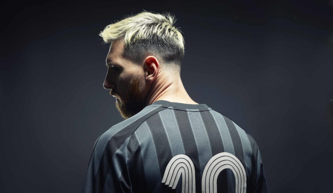 Man in a soccer jersey with number 10 on the back, close-up shot with hair bleached blonde and a dark background.