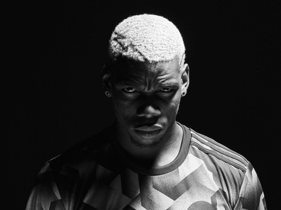 Striking black and white portrait of an adult male with light hair, wearing a patterned jersey, against a stark black background.