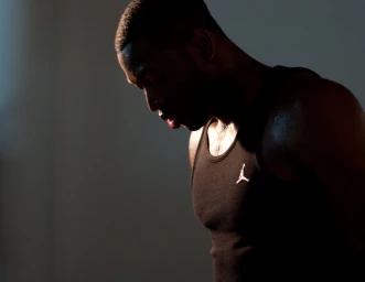 Close-up portrait of a Black man in a black tank top with side lighting, captured by The Wade Brothers in London.