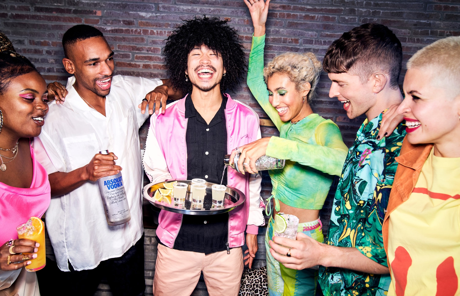 Diverse group of friends celebrates with cocktails and drinks in a bar setting, enjoying each other's company and vibrant atmosphere.