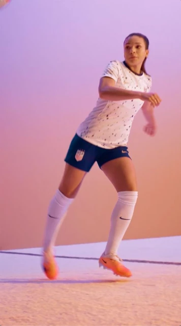Female soccer player in US national team uniform in action, captured in a vibrant, dynamic studio setting. Focus on athletic performance.