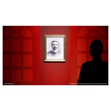 Monochrome portrait in a gold frame hanging on a vibrant red wall next to a human silhouette, in a simple indoor setting.