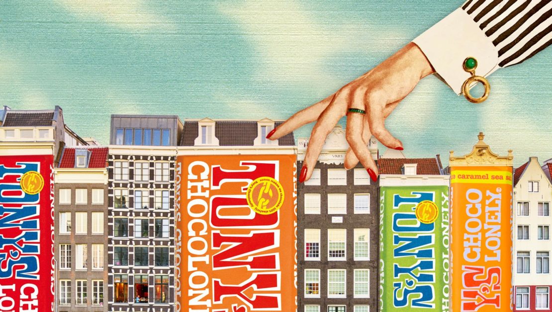 Digital art featuring Tony's Chocolonely chocolate bars designed like buildings, with a female hand walking across them, set against a blue sky.