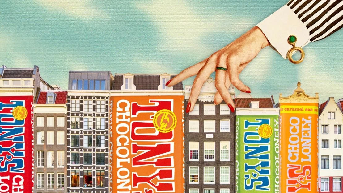 Digital art featuring Tony's Chocolonely chocolate bars designed like buildings, with a female hand walking across them, set against a blue sky.