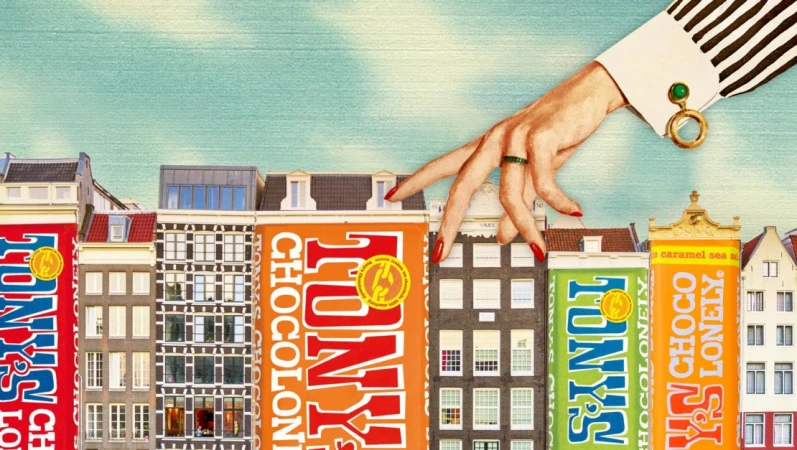 Digital art featuring Tony's Chocolonely chocolate bars designed like buildings, with a female hand walking across them, set against a blue sky.