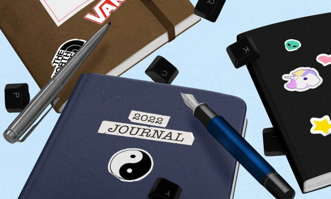 A variety of journals and pens are scattered across a light blue background, with various stickers and keyboard keys accenting the scene.