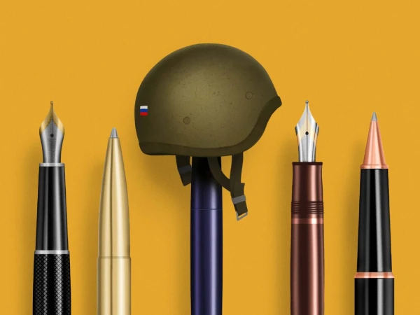 Fountain pens and ballpoint pens stand upright in a row next to a military helmet with the Russian flag on an orange background.