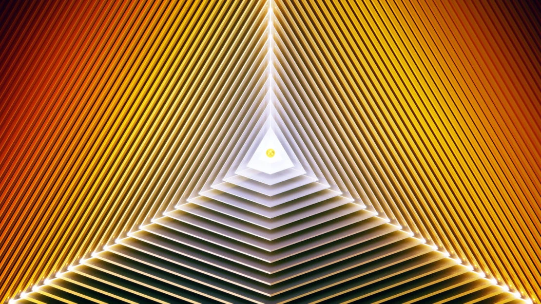 Abstract image featuring a layered, triangular tunnel with orange and yellow hues, creating a sense of depth and geometric patterns.