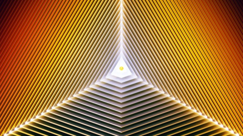 Abstract image featuring a layered, triangular tunnel with orange and yellow hues, creating a sense of depth and geometric patterns.