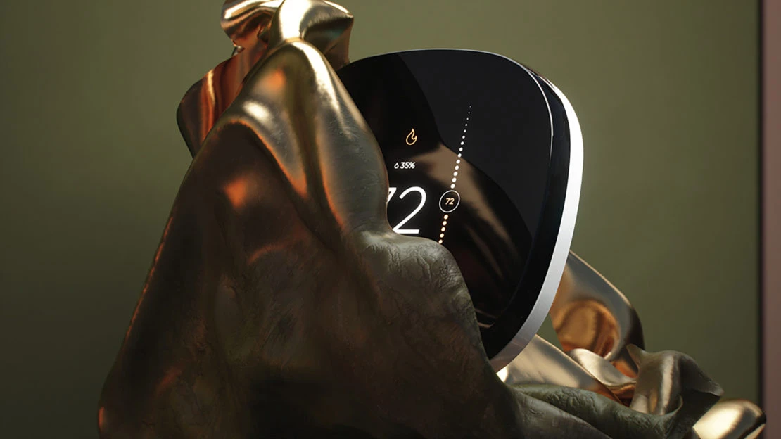 Sleek black smart thermostat surrounded by gold cloth, showing a digital display of 72 degrees in an indoor environment.