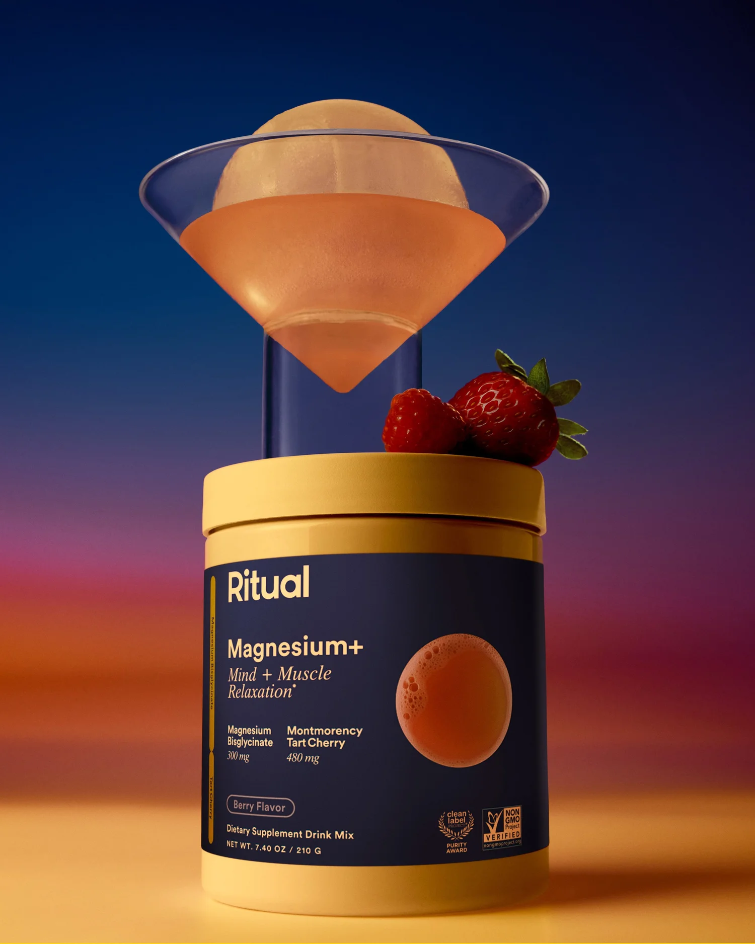 Product shot of Ritual Magnesium supplement drink mix next to martini glass and fresh berries against blue and orange gradient backdrop.