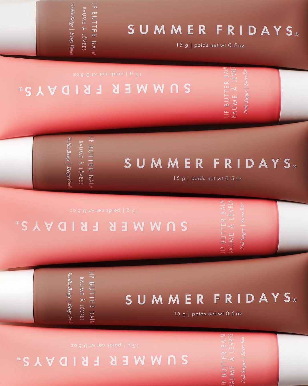 Cosmetic product still life: Close-up of Summer Fridays Lip Butter Balm tubes in pink and brown, stacked in a studio product shot.