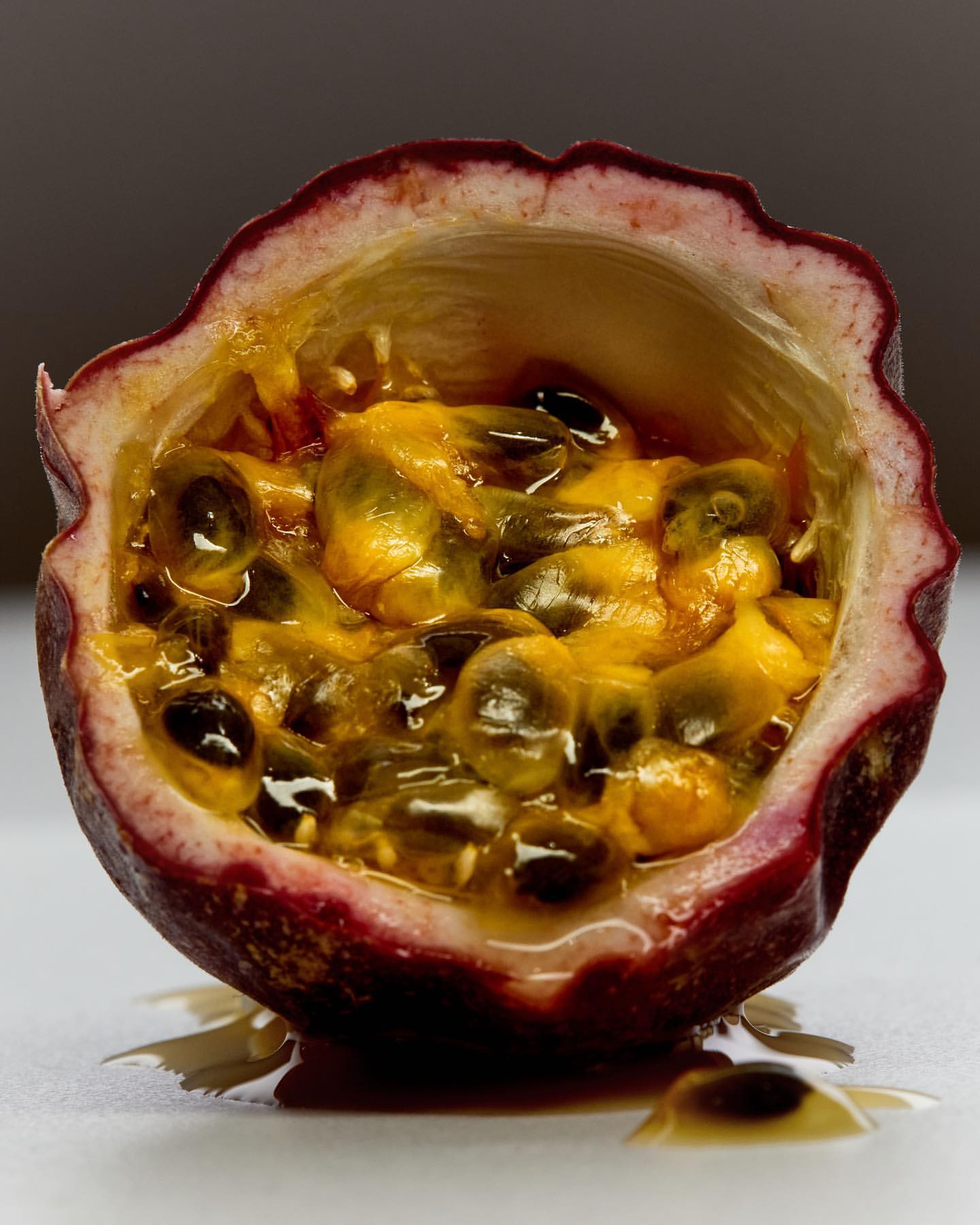 Close-up studio shot of a halved passion fruit with yellow pulp and black seeds, showcasing the fruit's texture and vibrant colors.