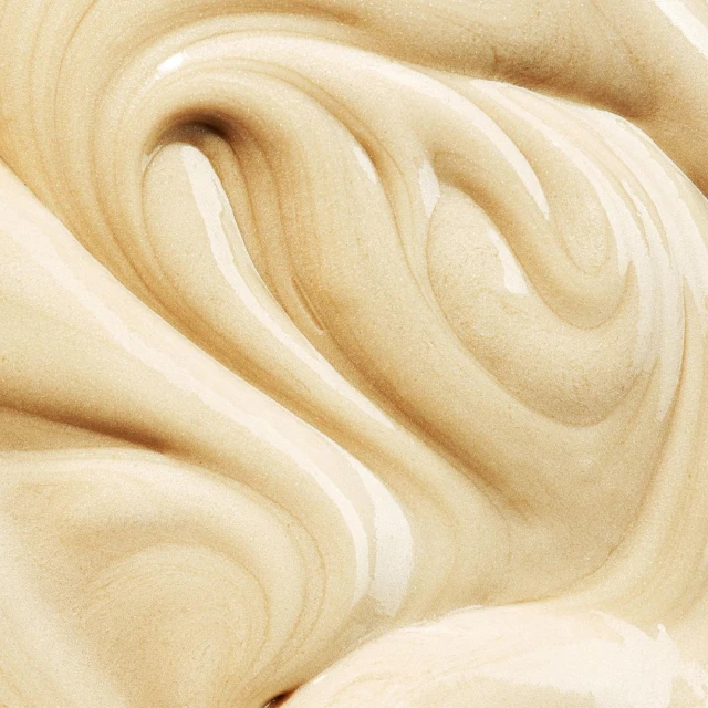 Close-up shot showcasing thick, smooth, pale beige lotion, creating swirling patterns with a glossy finish, ideal for beauty applications.