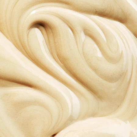Close-up shot showcasing thick, smooth, pale beige lotion, creating swirling patterns with a glossy finish, ideal for beauty applications.