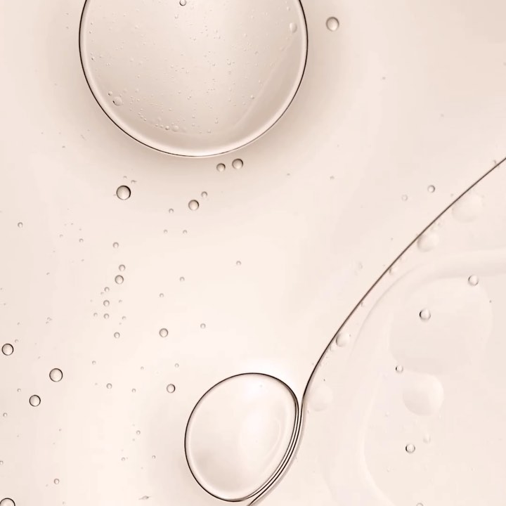 Abstract cosmetic background of transparent gel or serum with large and small bubbles on pale yellow background, skincare product.