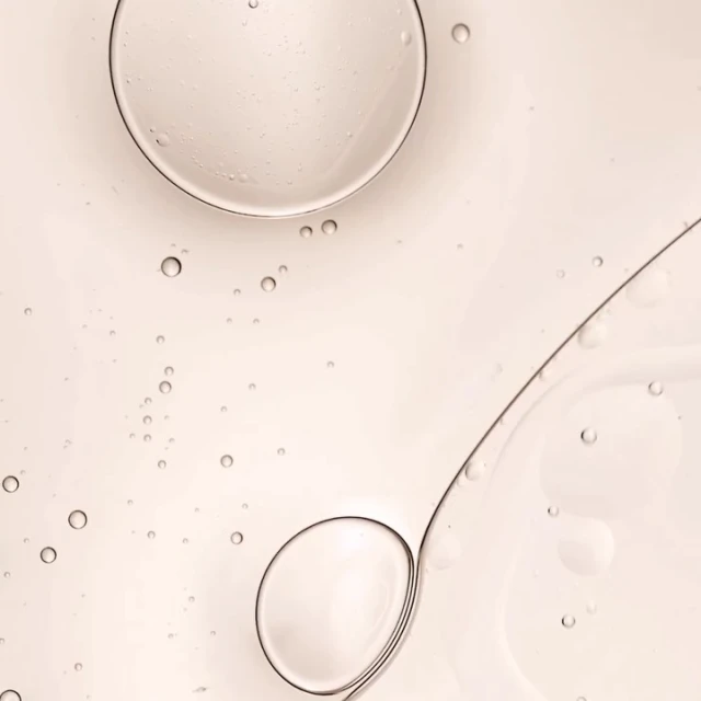 Abstract cosmetic background of transparent gel or serum with large and small bubbles on pale yellow background, skincare product.