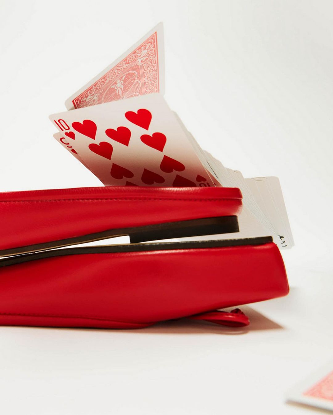 Fashion flat shoes styled with floating playing cards in a studio setup, creating a quirky and playful visual composition.