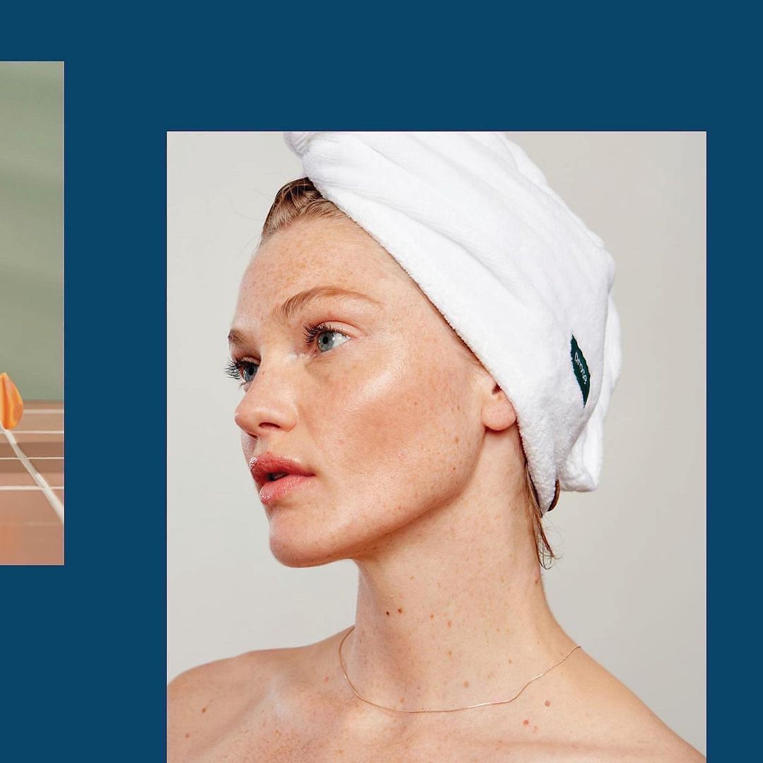 Close-up shot of a woman with a white towel wrapped around her head, showcasing a fresh, clean beauty aesthetic and soft, natural lighting.