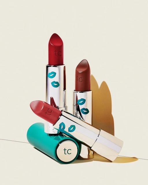 Close-up of assorted lipsticks with colorful packaging, illuminated by soft, diffused light against a neutral background.