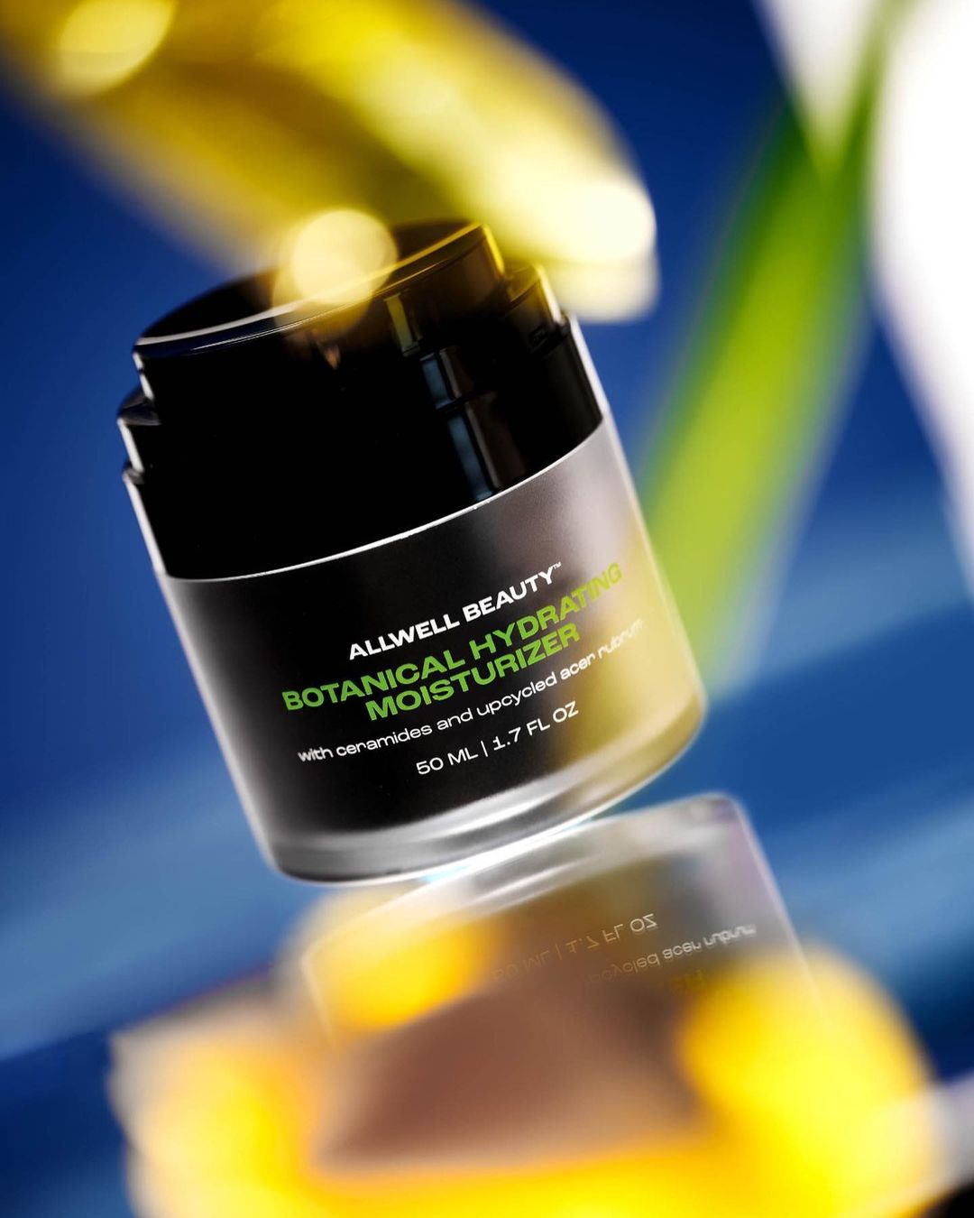 Close-up shot of a black and clear Allwell Beauty botanical hydrating moisturizer jar sitting on a reflective surface.