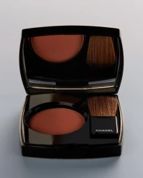 Open Chanel blush compact featuring a round pressed powder pan and a small cosmetic brush inside a black case.