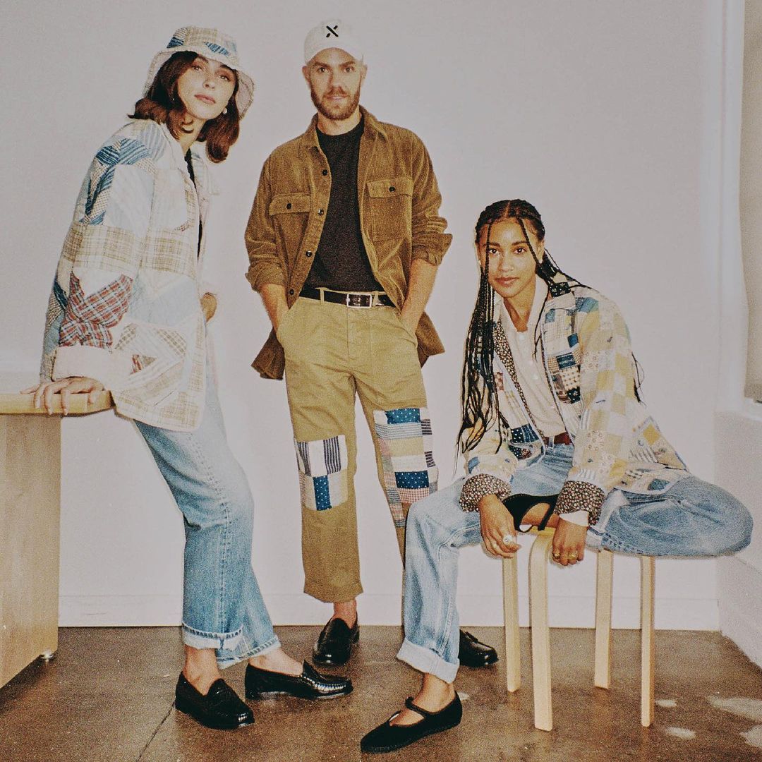 Three stylish people in a studio setting wearing patchwork-design jackets, jeans, and corduroy pants and jacket in a fashion pose.