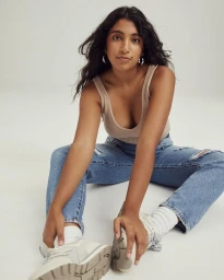 Woman seated on floor wearing ribbed tank top, distressed denim jeans, and sneakers by Felisha Tolentino