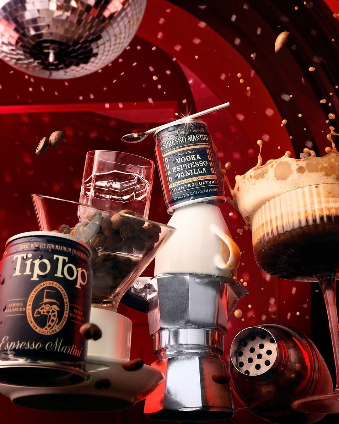 Still life of espresso martini ingredients featuring coffee beans, a cocktail shaker, moka pot, and a disco ball against a red backdrop.
