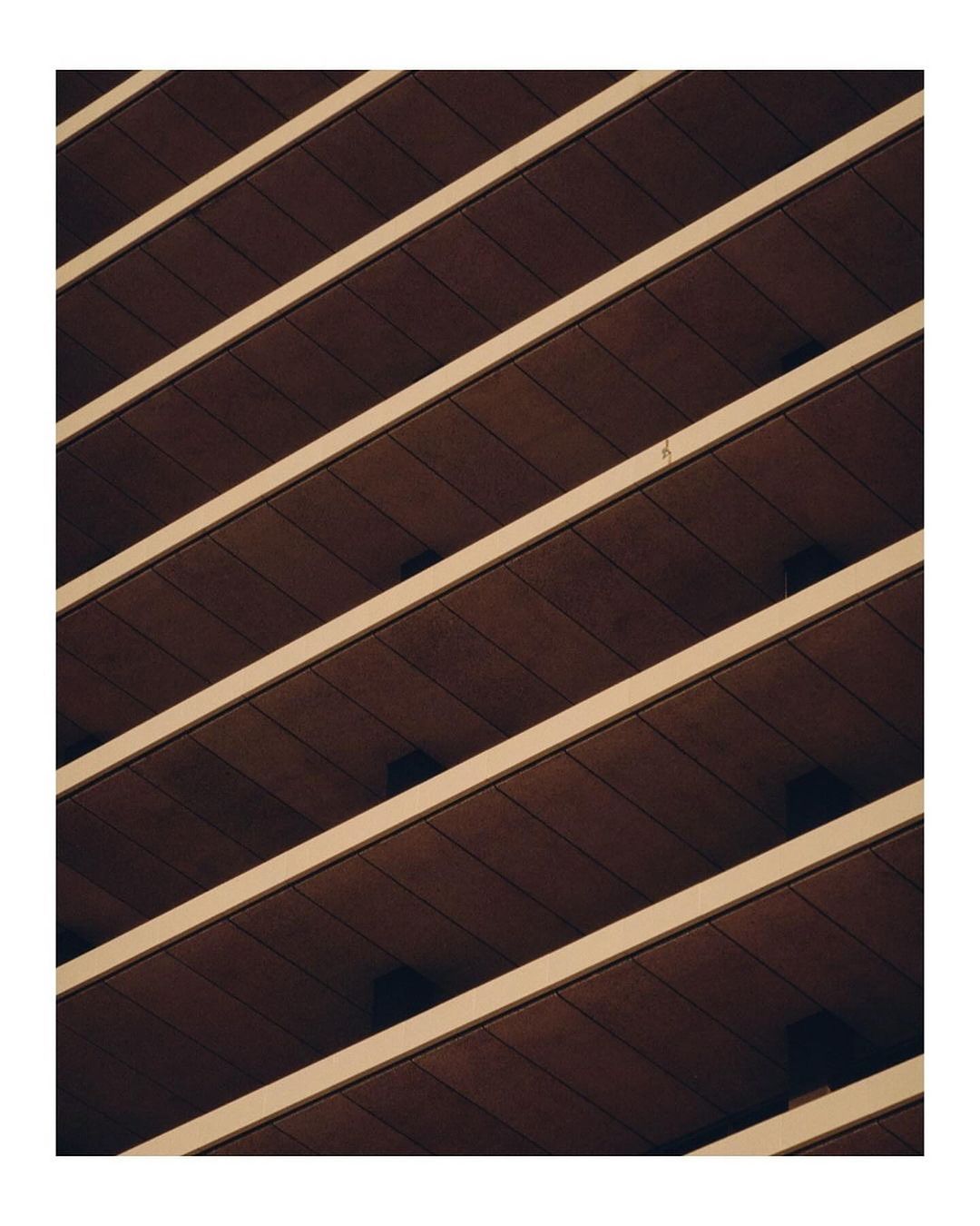 Oblique view showcases an architectural facade with horizontal brown panels and white structural elements, emphasizing geometric patterns.