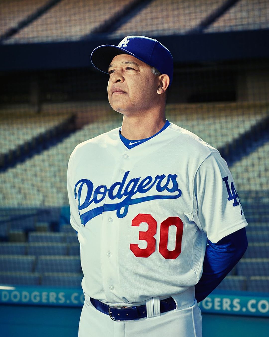 Portrait of a baseball player in a Dodgers uniform with the number 30 standing on a baseball field, looking off camera.