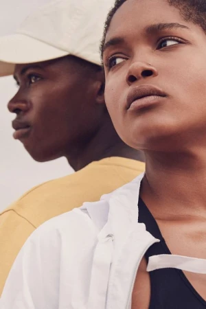 Close-up portrait of two young models outdoors with a pale sky background, shot by Aaron Smith.