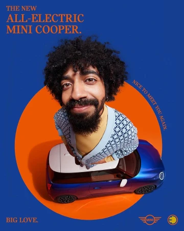 Person with an afro smiling above a blue Mini Cooper car, set against an orange and blue background in a studio shot.