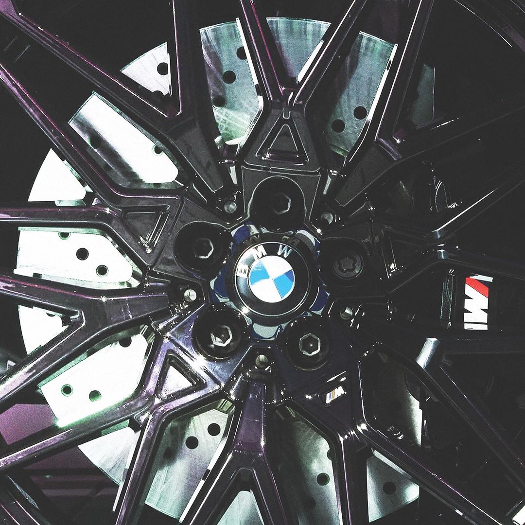 Close-up of a black BMW car wheel with silver brake rotor, showcasing the design and mechanics of the vehicle's components.