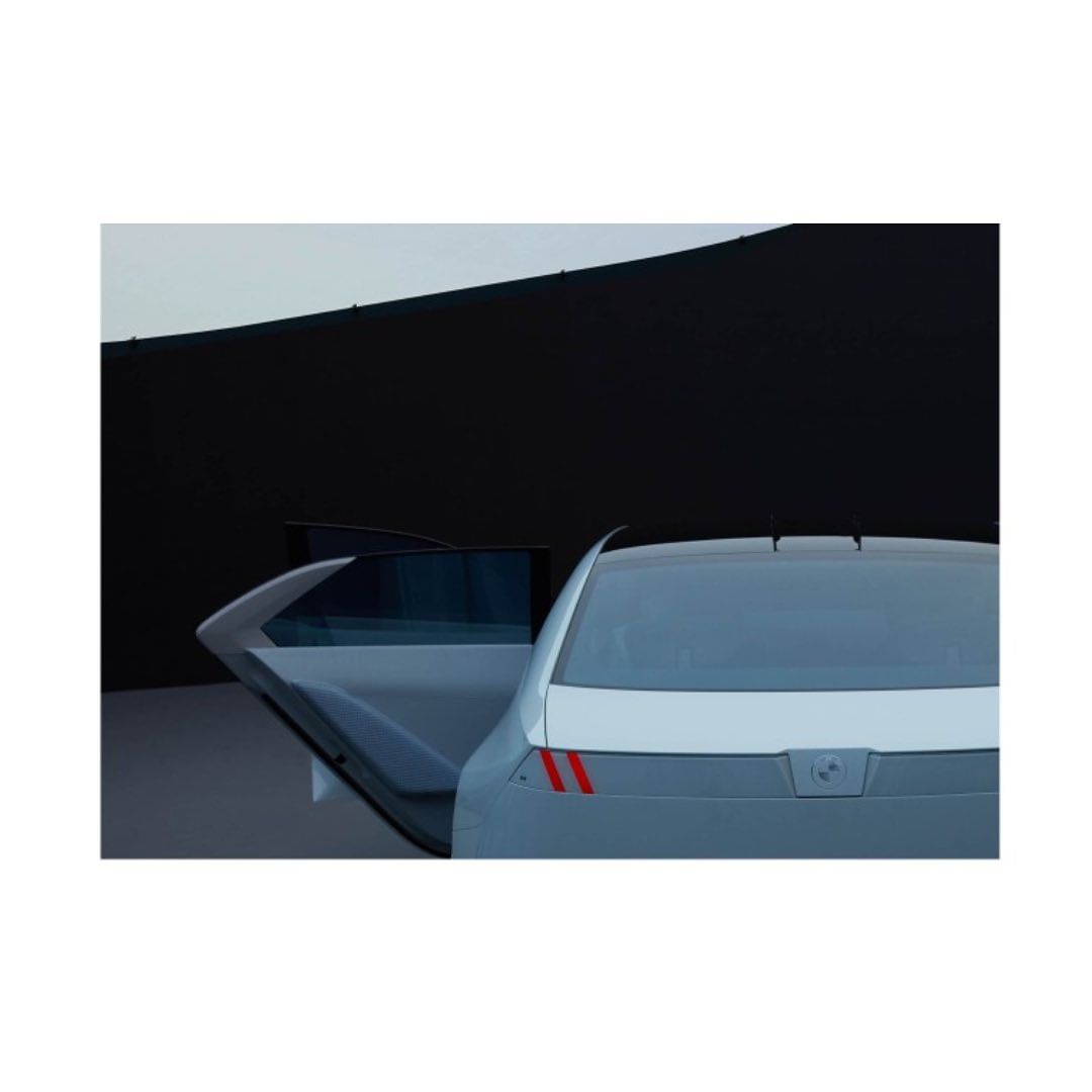 Sleek silver car showcased in front of a minimalist black wall with an open rear door, creating a striking modern automotive image.