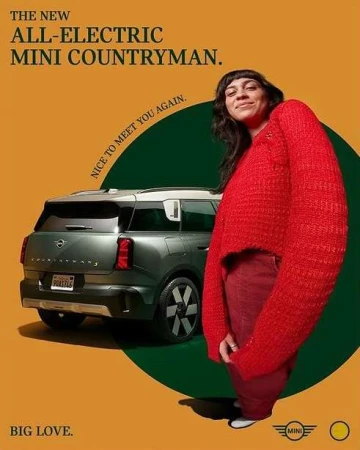 All-electric Mini Countryman advertisement featuring a woman in a red knit sweater standing next to the vehicle, set against a yellow and green background.