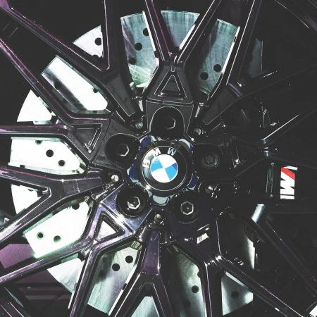 Close-up shot of a black BMW alloy wheel featuring multi-spoke design, perforated brake disc, and centered BMW roundel emblem.