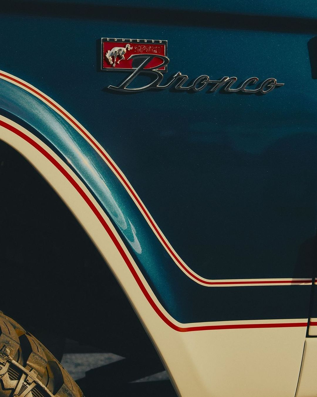 Close-up of a vintage blue and white Ford Bronco with the Bronco emblem, showcasing automotive design and classic vehicle aesthetics.